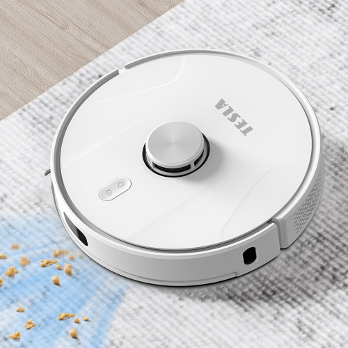 Robotický vysavač TESLA RoboStar IQ700 vysává cereálie na bílém koberci.