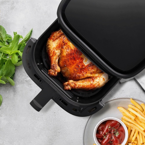 Horkovzdušná fritéza TESLA AirCook Q55 XL PRO s celým pečeným kuřetem, otevřený koš, černá barva.